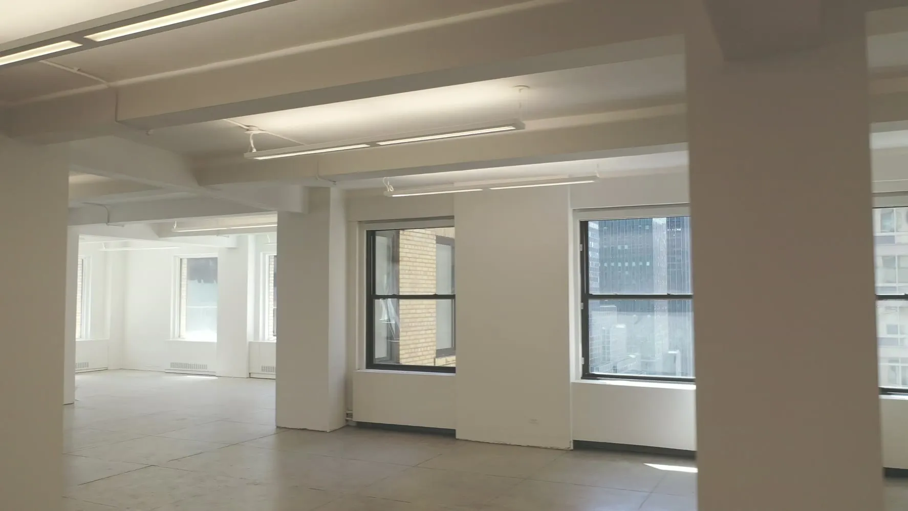 Bright empty office floor with white walls, columns and large windows