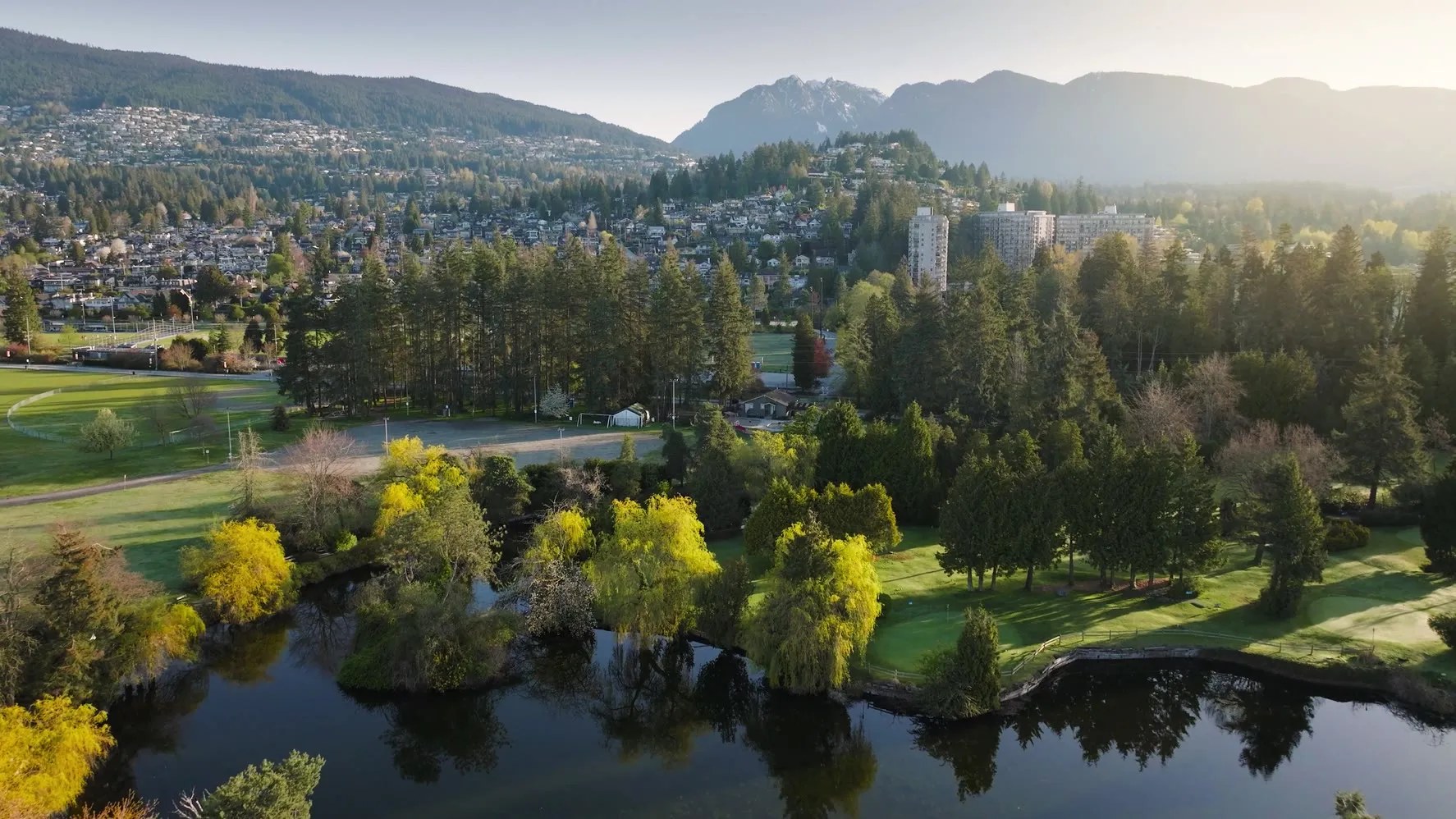 Aerial view of West Vancouver at dawn with mountains, trees and a golf course