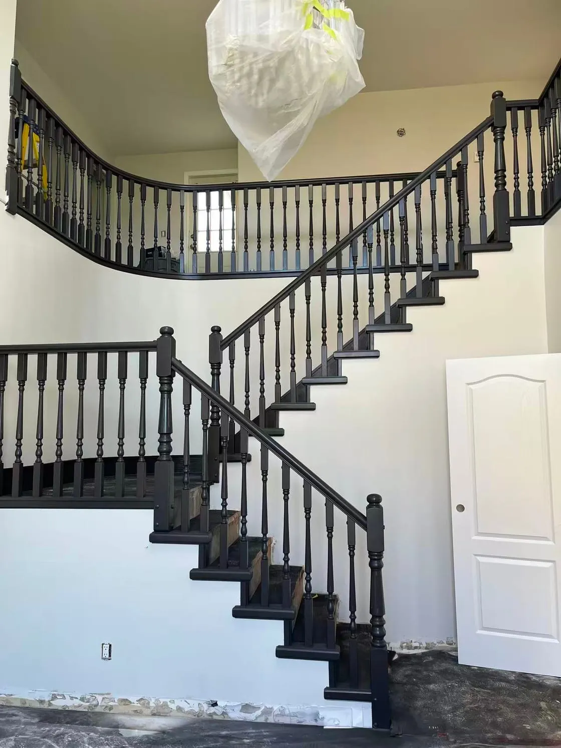 Interior stairway during work, with pale walls and dark railings